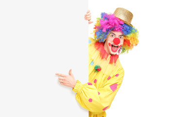 Funny circus clown posing behind a blank panel
