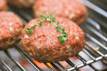 raw burgers on bbq  barbecue grill with fire