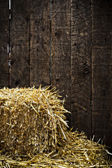 Bale of straw and wooden background