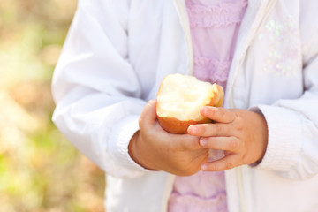 beautiful little girl eating apple in the autumn forest