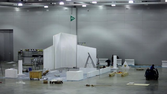 Few workers build exhibition stand, cleaning machine ride