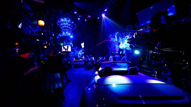 Car standin dark night club with colorful illumination