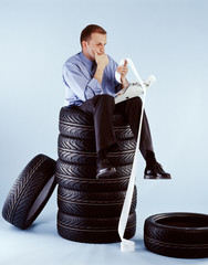 Mann sitzt auf Reifenstapel