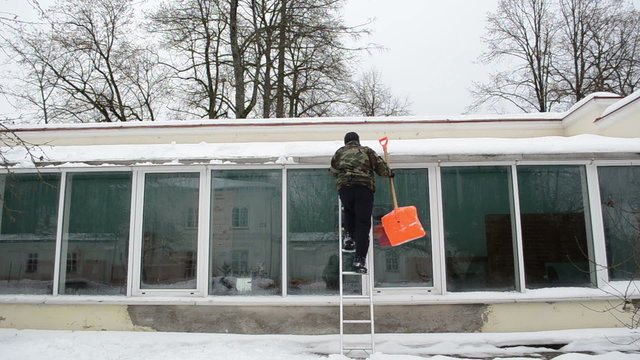 man ladder orange shovel tool clean snow greenhouse roof winter