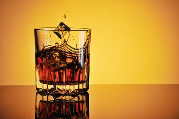 Foto op Canvas Glass of whisky with ice against yellow background © andriikoval