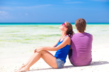beautiful young couple sitting and having fun on beach