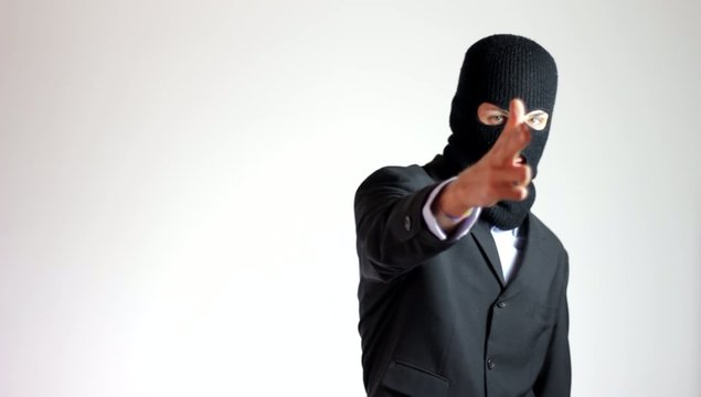uomo incappucciato punta la pistola