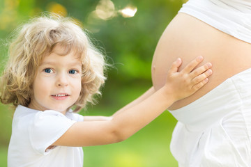 Child holding belly of pregnant woman