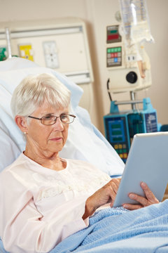 Senior Patient Relaxing In Hospital Bed With Digital Tablet