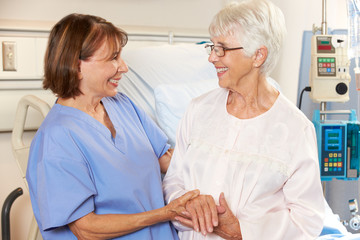 Obraz premium Nurse Talking To Senior Female Patient In Hospital Bed