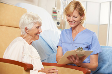 Fototapeta premium Nurse Taking Notes From Senior Female Patient Seated In Chair