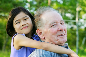 Little girl hugging her grandfather outdoors, diversity