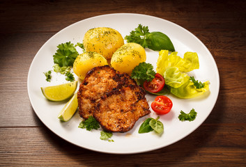 Grilled steaks, boiled potatoes and vegetables