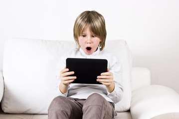 Surprised blonde boy with tablet