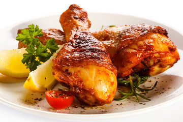 Grilled chicken legs and vegetables on white background