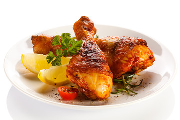 Grilled chicken legs and vegetables on white background