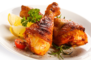 Grilled chicken legs and vegetables on white background