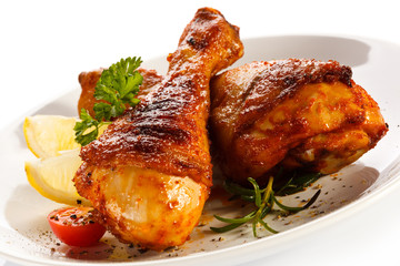 Grilled chicken legs and vegetables on white background
