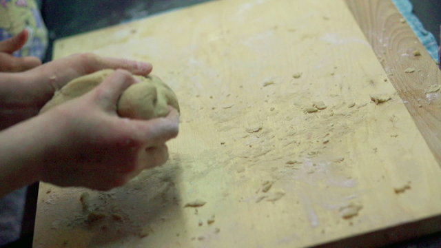 Small children hands with dough on wooden table with flour, slow