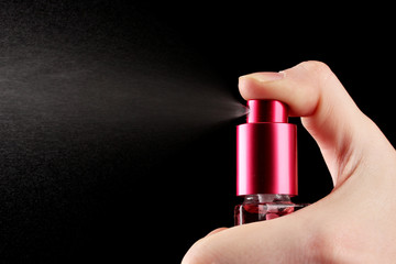 women's perfume in bottle and spraying, on black background