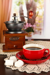 cup of coffee with scarf and coffee mill on table in room