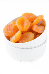 Isolated dried apricots in a white ceramic bowl
