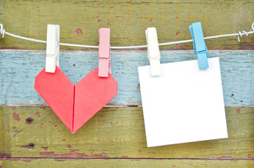 Paper heart and card hanging on the clothesline. On old wood bac