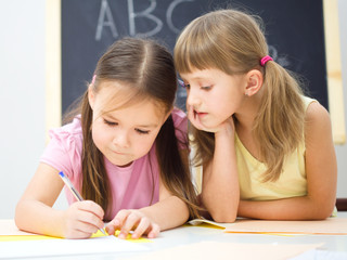 Little girls are writing using a pen