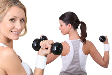 Two women lifting weights together