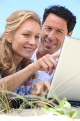Couple looking at laptop outdoors.