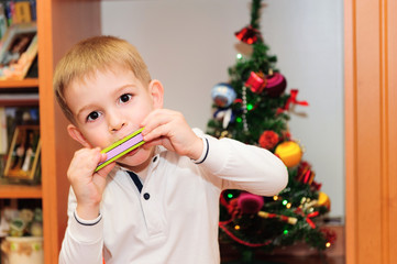 Cute little boy playing on harmonica