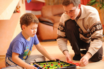 Fototapeta premium Boy and his father playing board soccer game at home