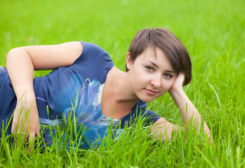 Naklejka na ściany i meble Young Woman relaxing on the green grass