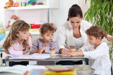 Woman helping a group of girls with their homework - obrazy, fototapety, plakaty
