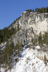 Fototapeta na wymiar Snow near granite cliff.