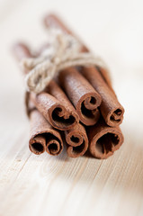 Bundle of cinnamon sticks on a wooden background, close-up
