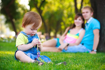 baby is plaing in a beautiful summer park - obrazy, fototapety, plakaty