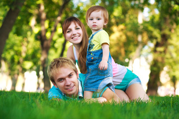 baby with parents in a green summer park