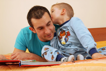 Padre e hijo compartiendo y leyendo un cuento. - obrazy, fototapety, plakaty