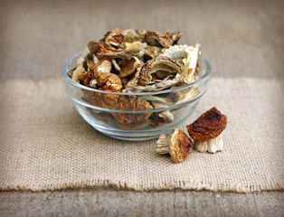 Dried mushrooms in glass bowl on wooden background