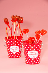 Valentine's day bucket with hearts and lollipops on pink 