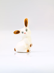 A ceramic doll of white rabbit with light brown spots isolated o