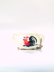 A miniature ceramic jar keychain with chicken pattern isolated o