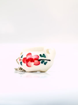 A miniature ceramic jar keychain with flower pattern isolated on
