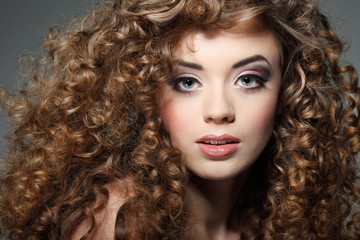 Fototapeta premium Young beautiful woman with long curly hairs
