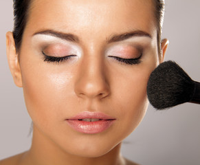 Portrait of attractive young adult woman applying blusher