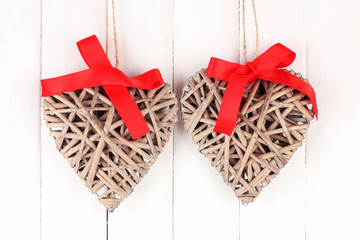 Wicker hearts with red bow on wooden background