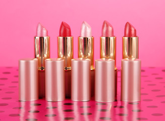 Lipsticks on table on pink background