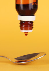 Medical droplet in spoon on yellow background