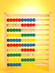 Bright wooden toy abacus, on yellow background
